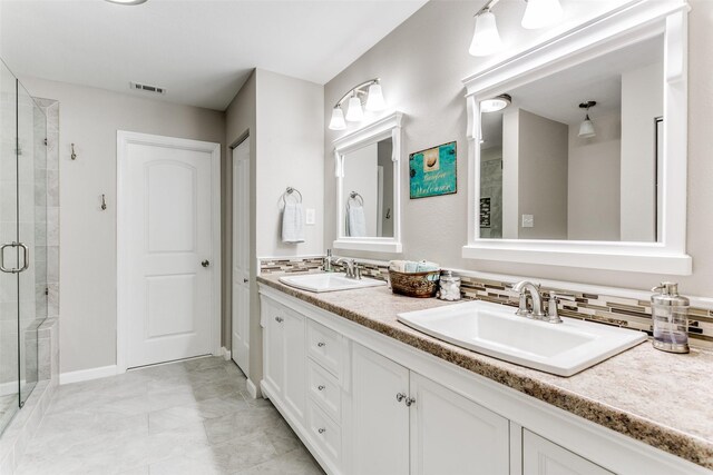 bathroom with dual vanity, decorative backsplash, tile patterned flooring, and a shower with shower door