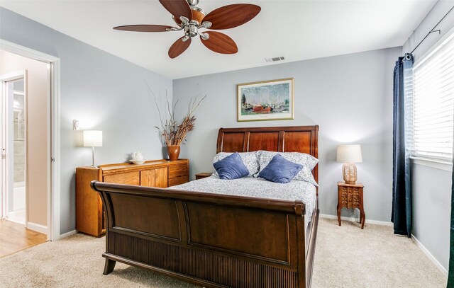 carpeted bedroom with connected bathroom, ceiling fan, and multiple windows