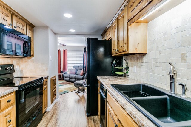 kitchen featuring black appliances, decorative backsplash, light hardwood / wood-style flooring, and sink