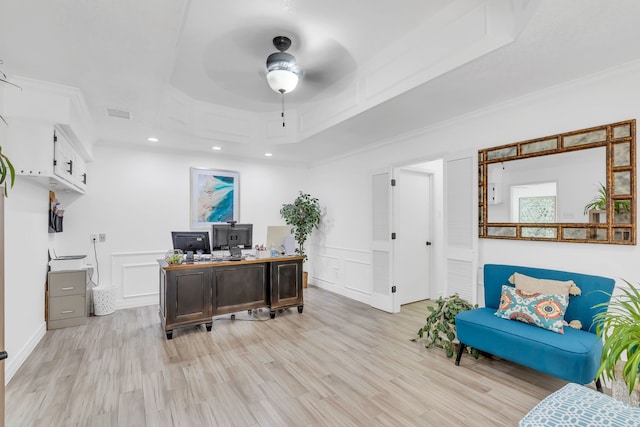 office featuring ceiling fan, light wood-type flooring, ornamental molding, and a tray ceiling