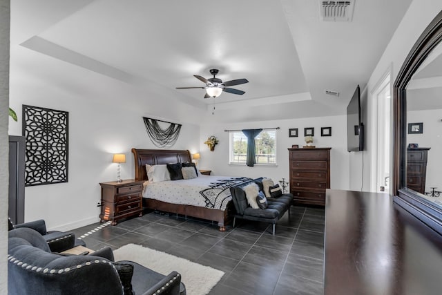 bedroom with a tray ceiling, ceiling fan, and dark tile patterned floors