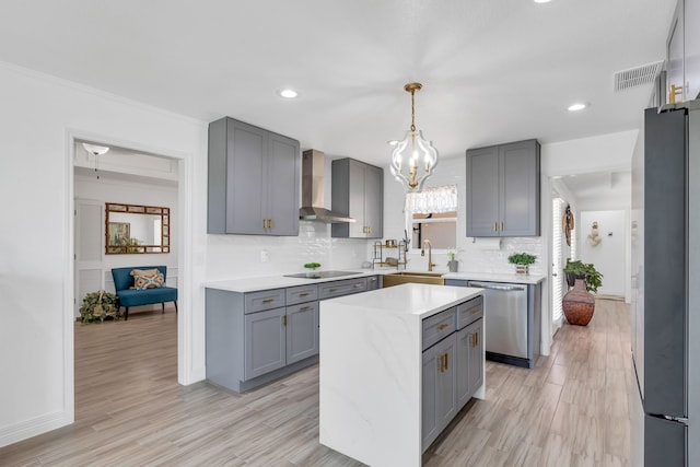 kitchen with wall chimney range hood, tasteful backsplash, black appliances, and light hardwood / wood-style floors