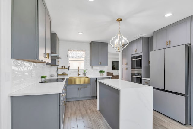 kitchen with white refrigerator, backsplash, light wood-type flooring, and sink