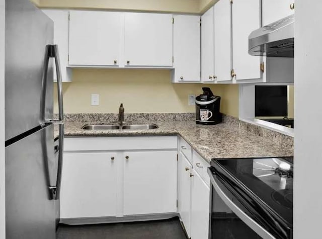 kitchen featuring white cabinets, wall chimney range hood, stainless steel refrigerator, range with electric cooktop, and sink