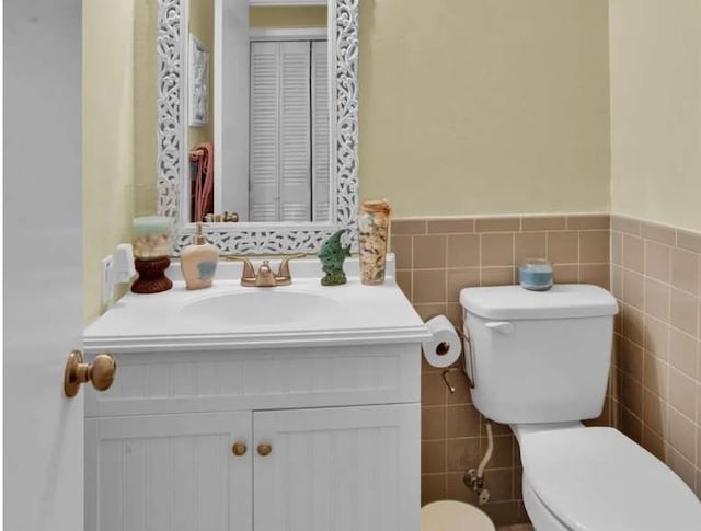 bathroom featuring vanity, tile walls, and toilet