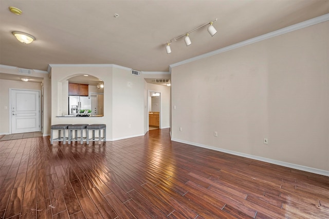 unfurnished living room featuring wood-type flooring, ornamental molding, and rail lighting