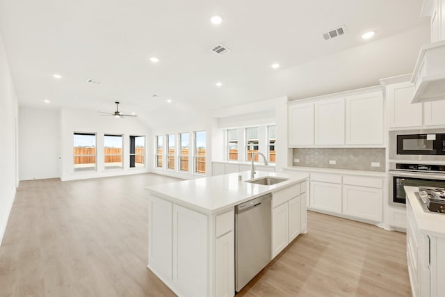 kitchen with white cabinets, appliances with stainless steel finishes, sink, and a kitchen island with sink