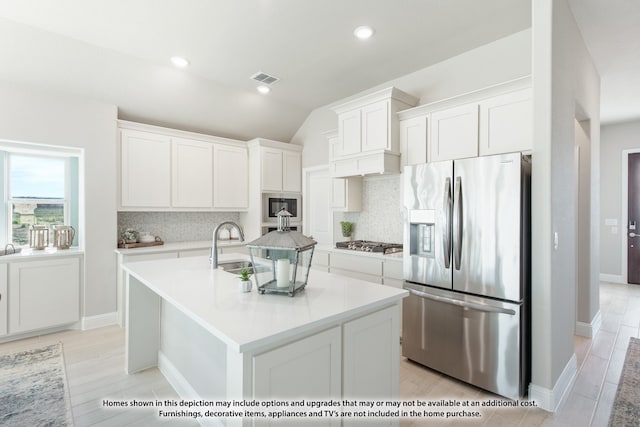 kitchen featuring tasteful backsplash, stainless steel appliances, white cabinets, and a center island with sink