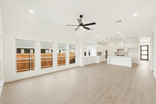 unfurnished living room featuring ceiling fan, light hardwood / wood-style flooring, a wealth of natural light, and lofted ceiling