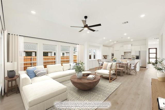 living room featuring light hardwood / wood-style floors, vaulted ceiling, and ceiling fan