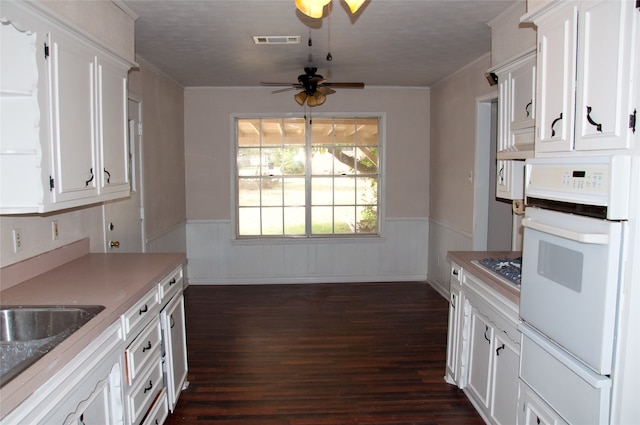 kitchen with dark wood-type flooring, white cabinets, ceiling fan, and oven