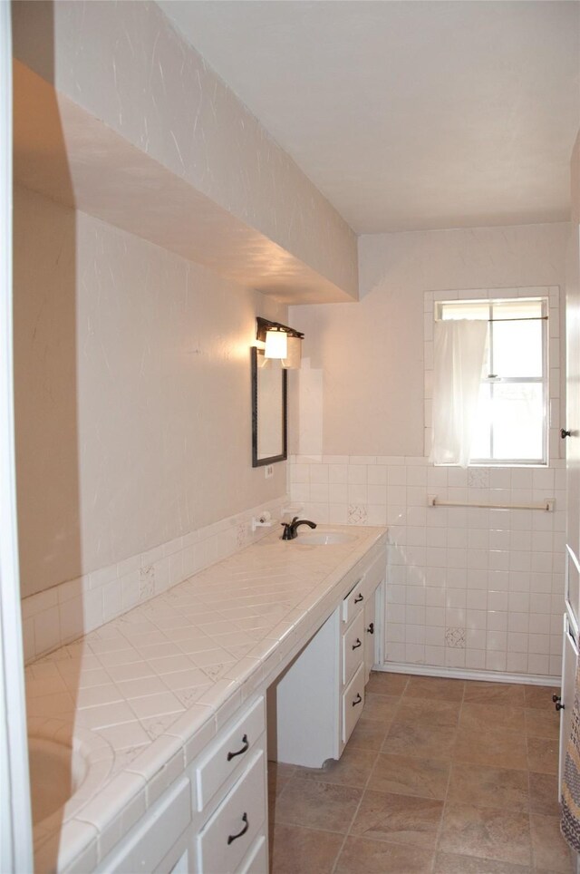 bathroom with vanity and tile walls