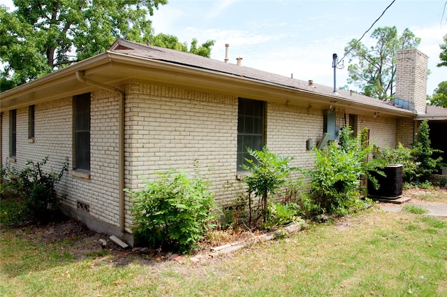 view of side of property with a yard and central AC