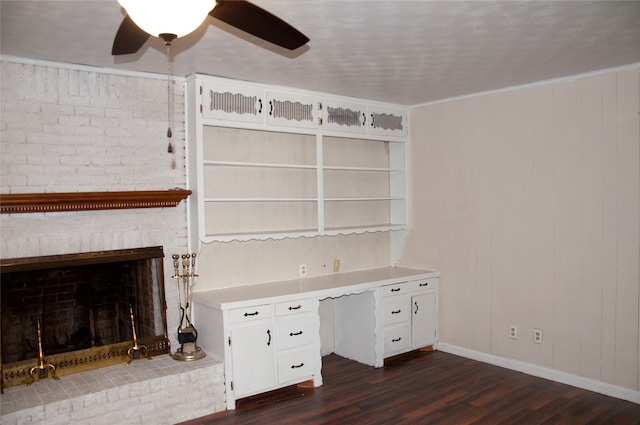 unfurnished office with ceiling fan, ornamental molding, a brick fireplace, and dark hardwood / wood-style flooring