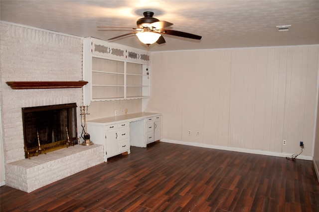 unfurnished living room with dark wood-type flooring, a textured ceiling, a brick fireplace, and ceiling fan