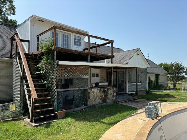 rear view of house featuring a lawn, a sunroom, and a patio area