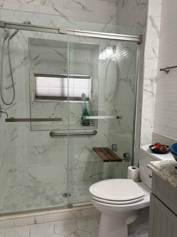 bathroom featuring toilet, radiator, tile patterned flooring, a shower with door, and vanity