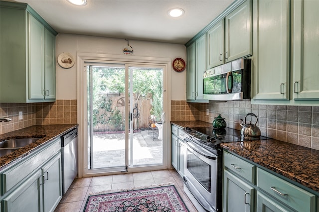 kitchen with light tile patterned floors, stainless steel appliances, green cabinets, and dark stone countertops