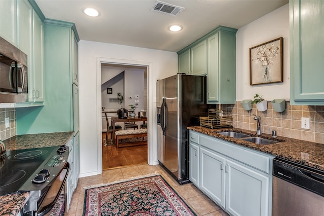 kitchen with decorative backsplash, appliances with stainless steel finishes, dark stone counters, light hardwood / wood-style floors, and sink