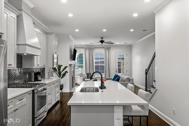 kitchen featuring appliances with stainless steel finishes, custom exhaust hood, a breakfast bar, sink, and a kitchen island