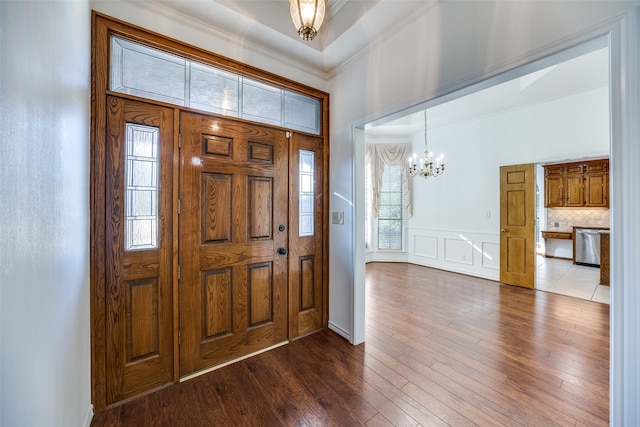 foyer entrance with ornamental molding, dark hardwood / wood-style flooring, and a chandelier