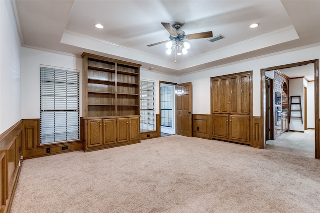 unfurnished room with a tray ceiling, ornamental molding, ceiling fan, and light colored carpet