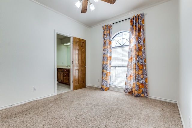 spare room featuring ceiling fan, a wealth of natural light, crown molding, and light colored carpet