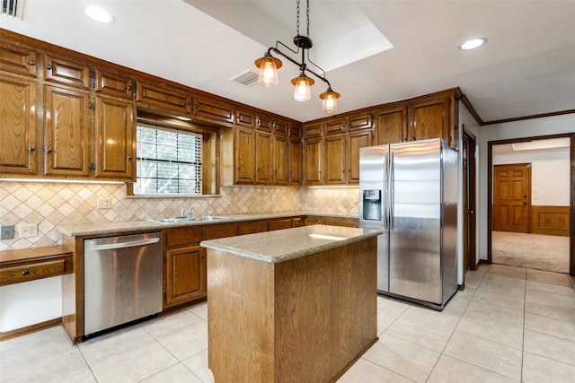 kitchen featuring decorative light fixtures, light stone countertops, stainless steel appliances, sink, and a kitchen island