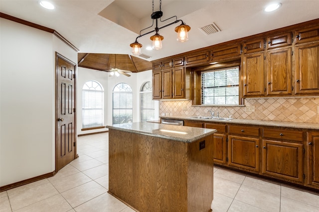 kitchen featuring light stone countertops, a healthy amount of sunlight, a center island, and ceiling fan