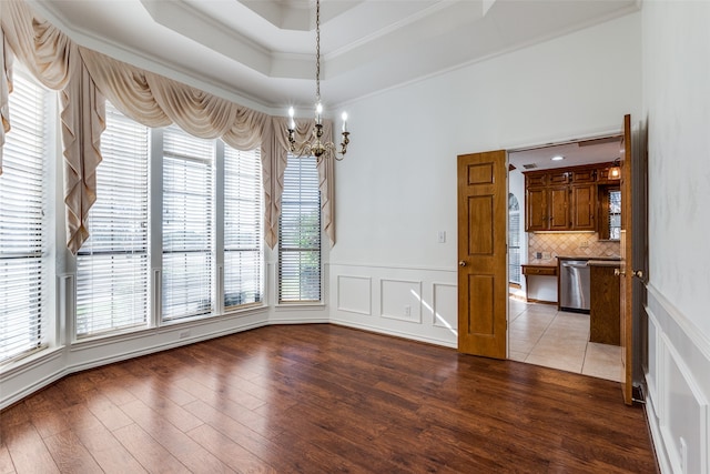 unfurnished dining area with ornamental molding, a healthy amount of sunlight, a notable chandelier, and hardwood / wood-style floors