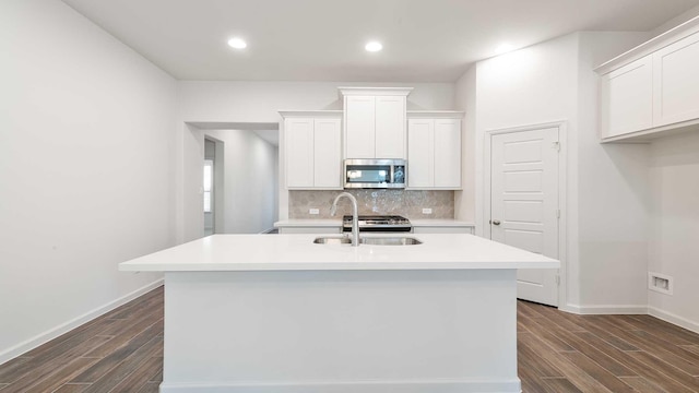 kitchen with decorative backsplash, appliances with stainless steel finishes, a kitchen island with sink, sink, and white cabinetry