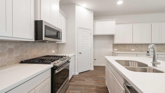 kitchen featuring decorative backsplash, white cabinetry, sink, and appliances with stainless steel finishes