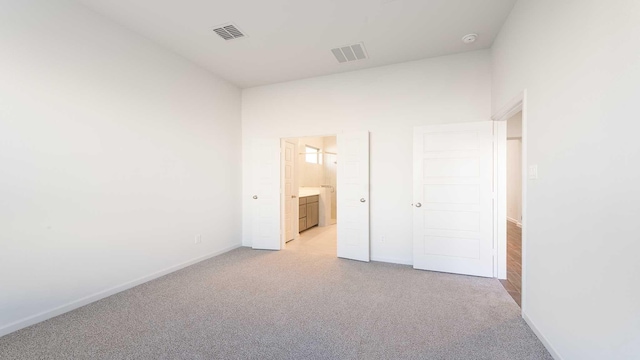 unfurnished bedroom with ensuite bath and light carpet