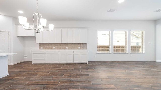 kitchen with backsplash, white cabinetry, pendant lighting, and a notable chandelier