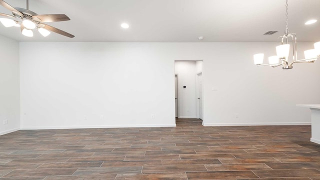 spare room featuring ceiling fan with notable chandelier