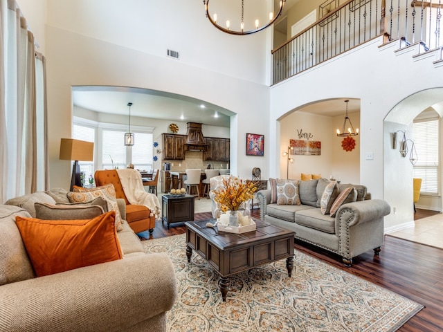 living room featuring light hardwood / wood-style flooring, plenty of natural light, a chandelier, and a high ceiling