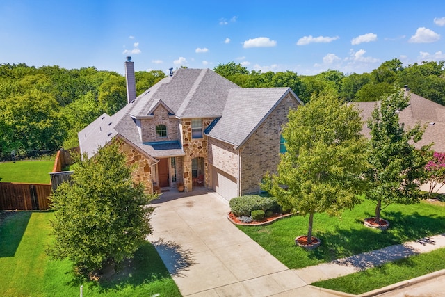 view of front of house featuring fence, concrete driveway, a front yard, a garage, and stone siding