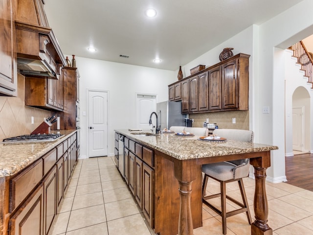 kitchen with a breakfast bar area, sink, stainless steel appliances, and light stone counters