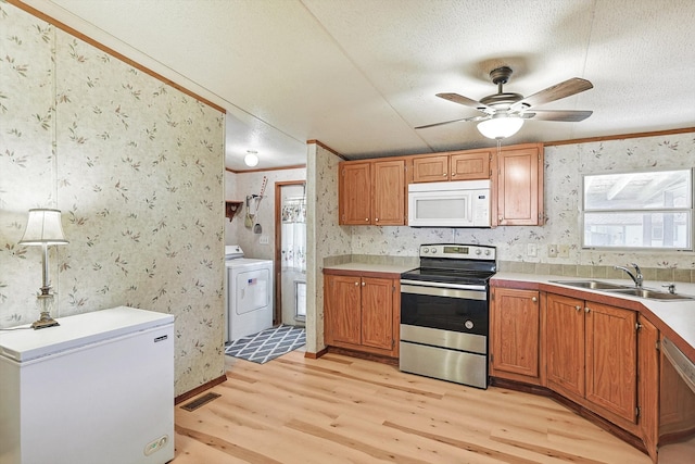 kitchen with appliances with stainless steel finishes, light wood-type flooring, washer / dryer, and ceiling fan