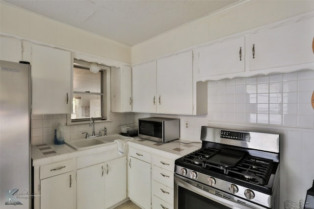 kitchen with appliances with stainless steel finishes, sink, tasteful backsplash, and white cabinetry