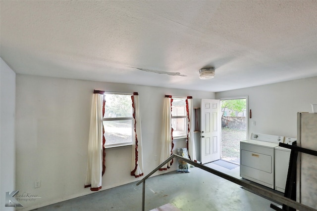 empty room with washing machine and dryer, concrete flooring, and a textured ceiling