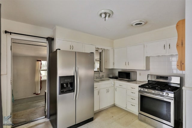 kitchen featuring tasteful backsplash, light tile patterned flooring, appliances with stainless steel finishes, white cabinets, and sink