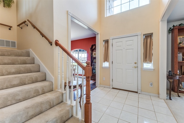 foyer featuring light tile patterned floors, a wealth of natural light, and a high ceiling