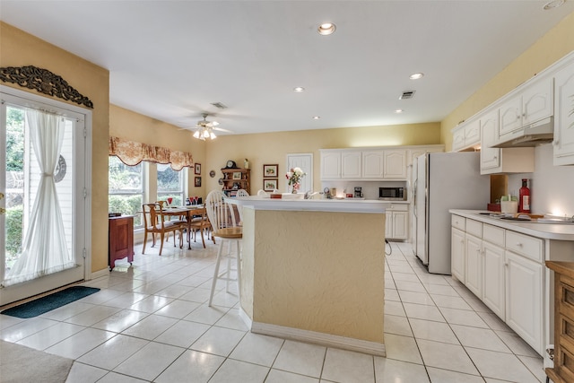 kitchen with white cabinets, light tile patterned floors, a center island, and ceiling fan