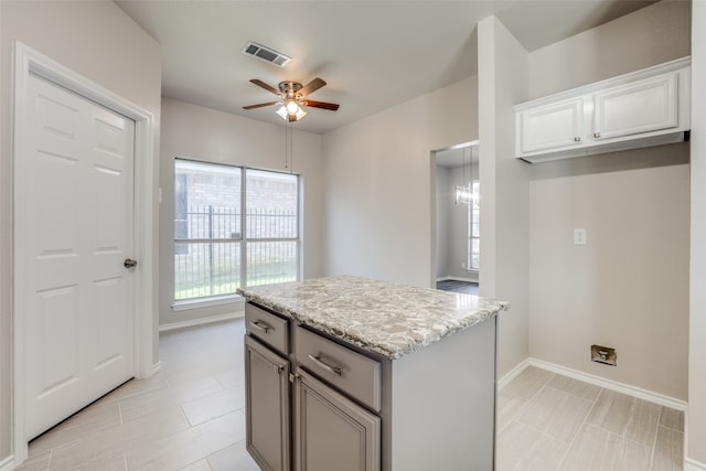 kitchen featuring gray cabinetry, ceiling fan, light stone countertops, and light tile patterned floors