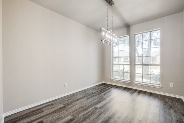 unfurnished dining area featuring dark hardwood / wood-style floors, a chandelier, and plenty of natural light