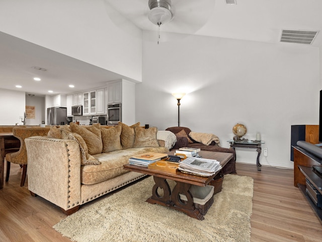 living room featuring light wood finished floors, baseboards, visible vents, a ceiling fan, and recessed lighting