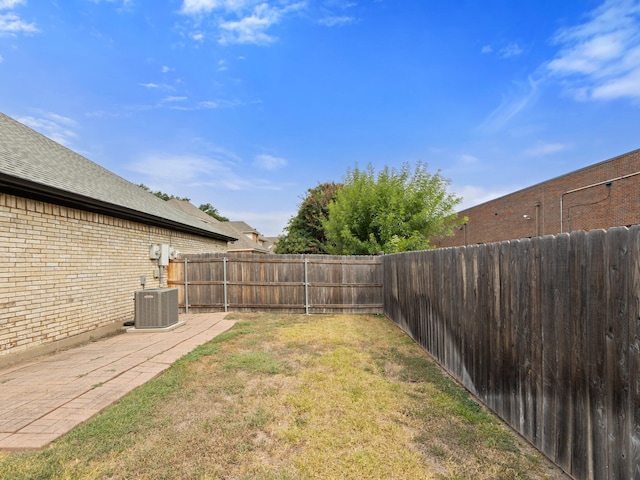 view of yard with a fenced backyard, a patio, and central AC unit