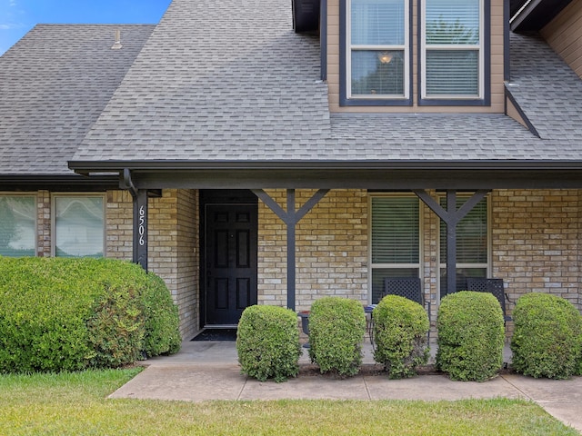 property entrance featuring brick siding and roof with shingles