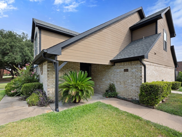 view of front facade featuring brick siding, roof with shingles, and a front yard